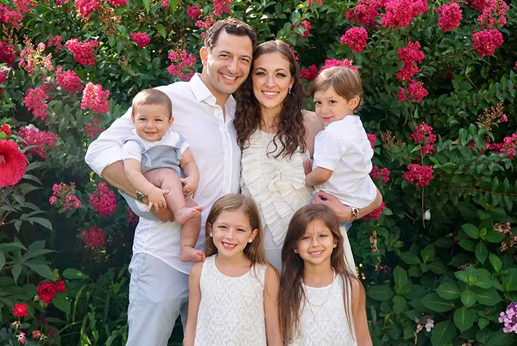 Dr. Eli Halabi, an orthodontist in Brooklyn posing with his beautiful wife and 4 children in front of red flowers