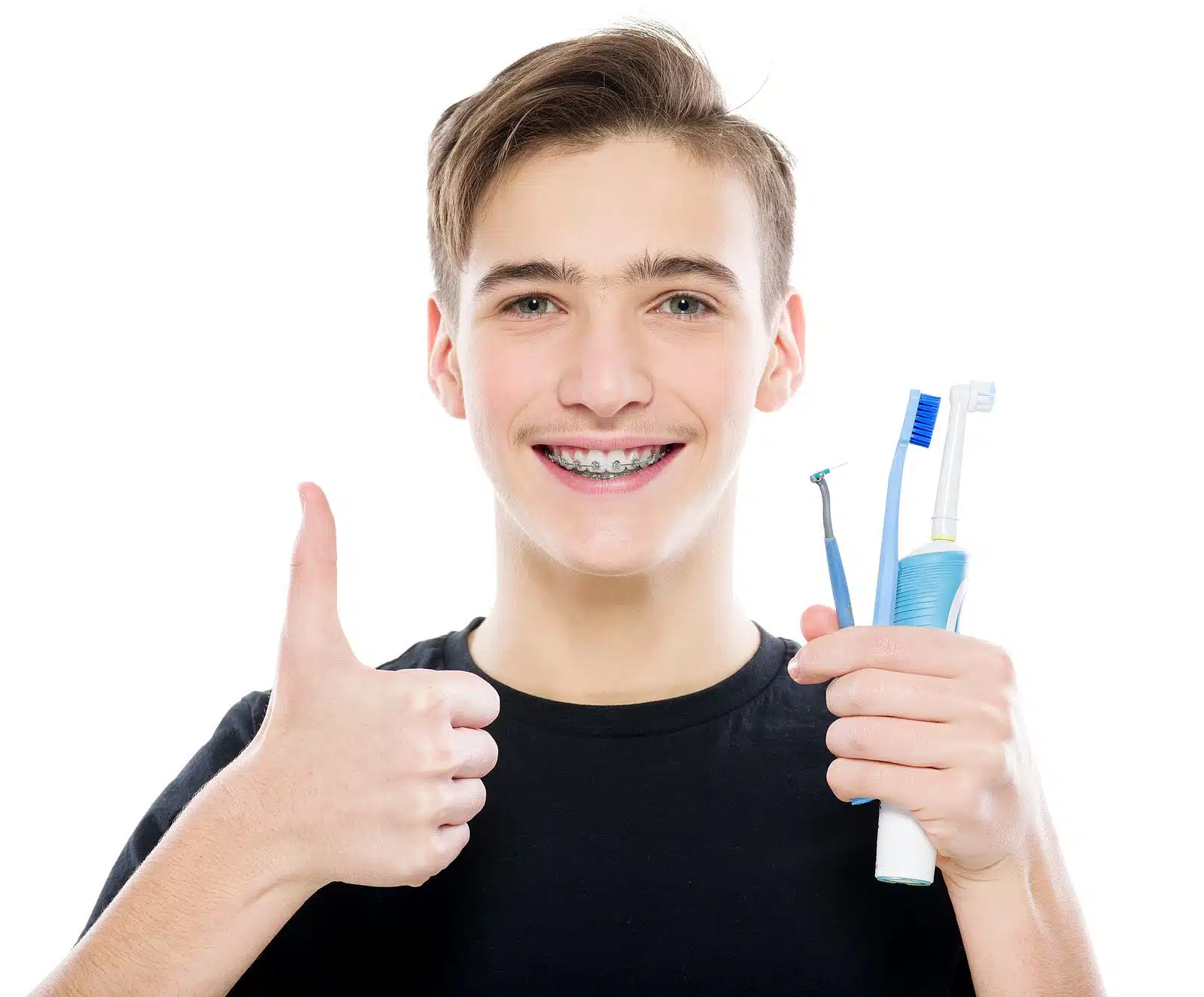 Teen boy holding a toothbrush and orthodontic cleaning tools, showing braces cleaning tips