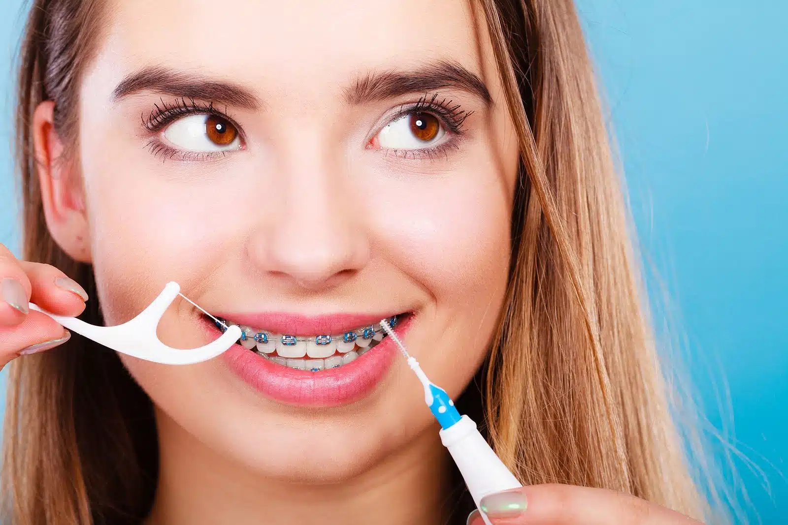 Woman cleaning her teeth with dental tools and practising oral hygiene with braces