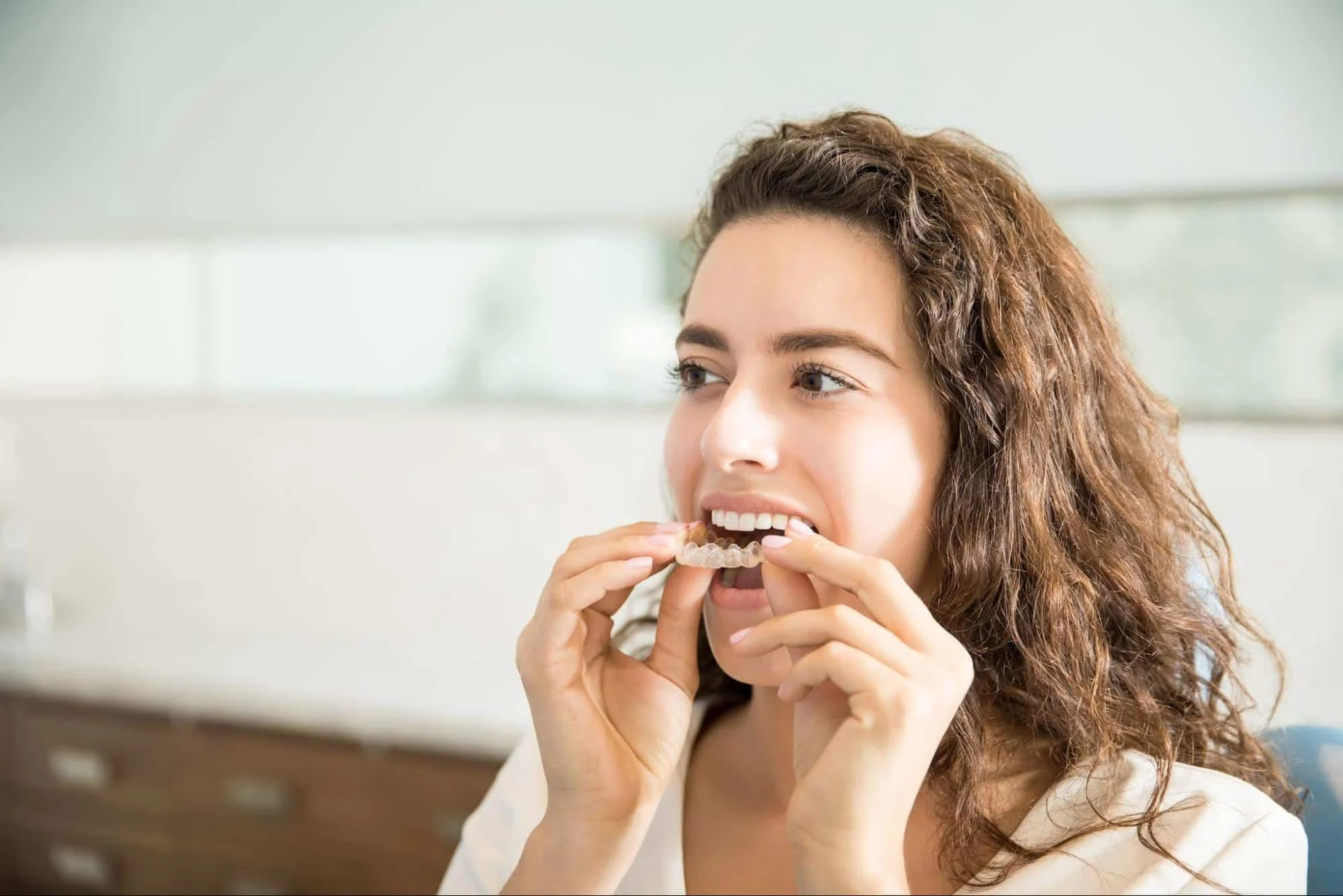 A close-up of a young woman's smile while wearing clear orthodontic aligners.