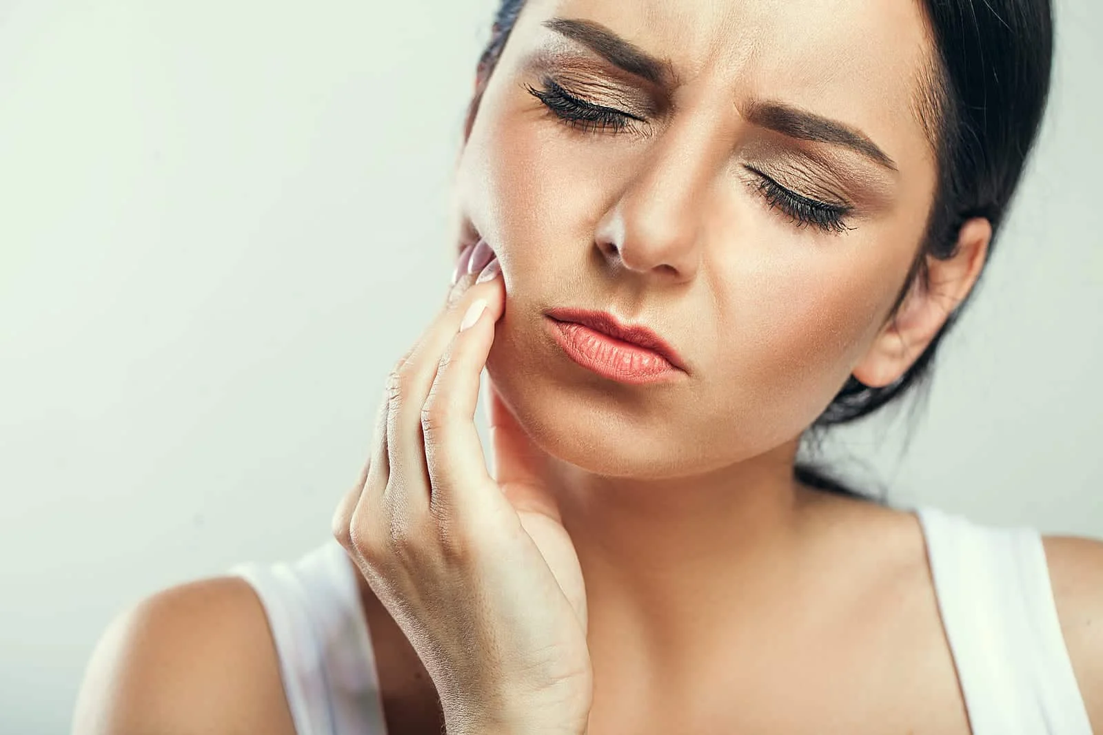 A young woman holding her cheek in pain